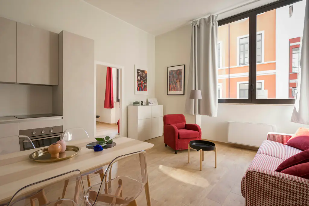 Compact furnished apartment with a dining table beside a street-facing window