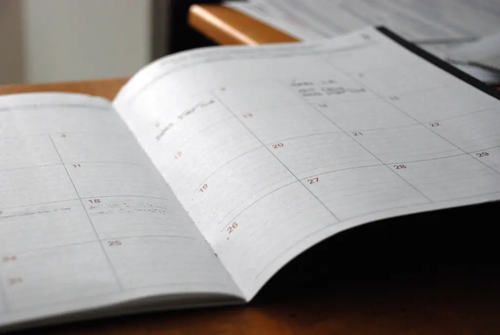 An open month-to-a-page paper planner on a timber desk