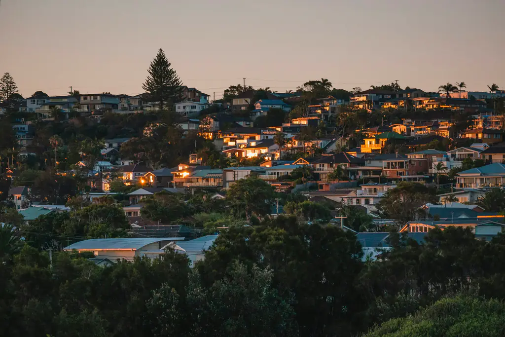 Houses stepped up a hillside at dusk, windows lit warm against the trees